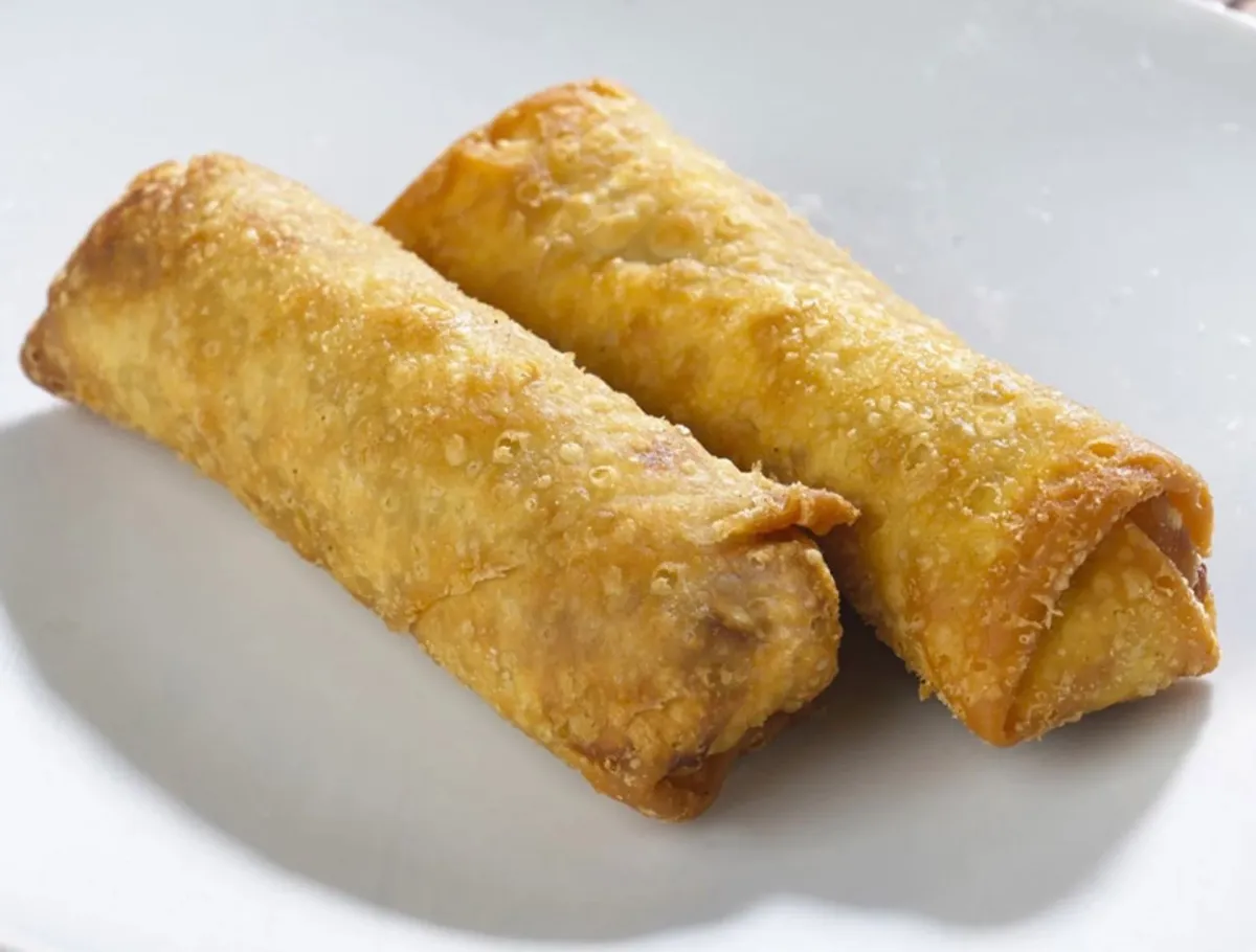 Two thick golden egg rolls on a white plate