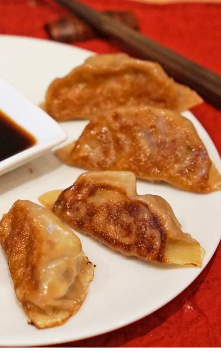 Pan-fried potstickers, crisped side up, with soy dipping sauce