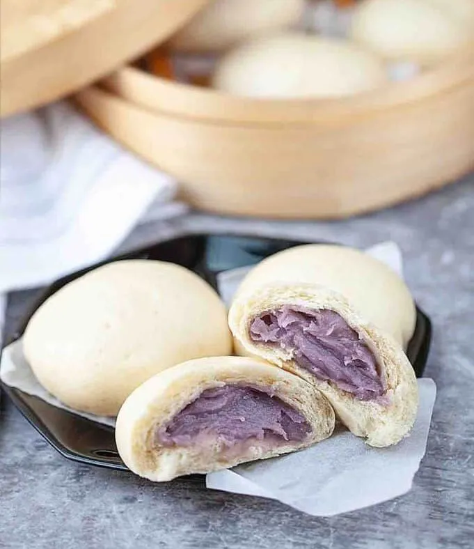 A steamed taro bun split open, purple taro filling inside